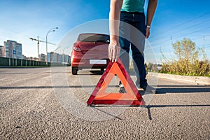 Man placing red triangle sing on road after car crash