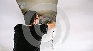 Man placing tube for kitchen hood installation on kitchen ceiling