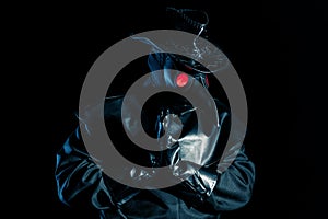 Man in plague doctor costume with crow-like mask praying with hands isolated on black background. Creepy mask photo