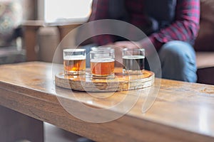 Man in plaid shirt sampling beer from a flight