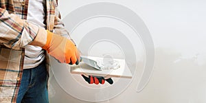 Man plastering wall using a construction trowel.