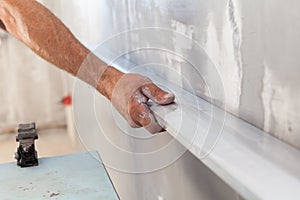 Man plastering a wall using floating rule to check the flatness