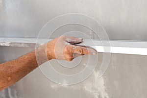 Man plastering a wall using floating rule to check the flatness. photo