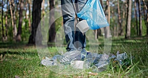 A man with a plastic bag collects garbage in the forest by heating it on a stick