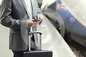 Man on the platform station. Typing text message on cell phone