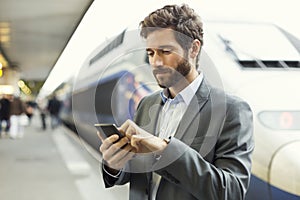 Man on platform station. Typing text message on mobile phone
