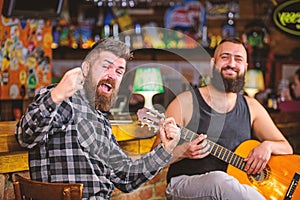 Man play guitar in pub. Live music concert. Acoustic performance in pub. Hipster brutal bearded with friend in pub