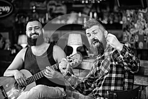 Man play guitar in pub. Live music concert. Acoustic performance in pub. Hipster brutal bearded with friend in pub