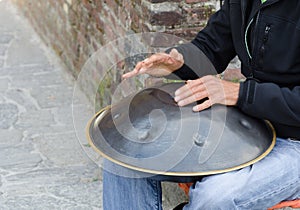 Man play instrument made of metal and called hang