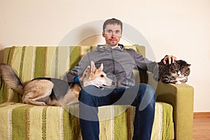 Man with playful dog and cat on sofa at home