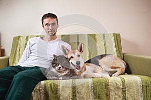 Man with playful dog and cat on sofa at home