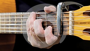 A man playing on acoustic guitar closeup and front view. A male musician plays the guitar