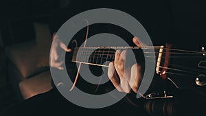 Man Playing Acoustic Guitar at Home in Atmospheric Dark Warm Lighting