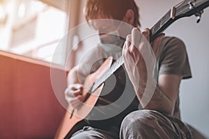 Man playing acoustic guitar in home quarantine self-isolation