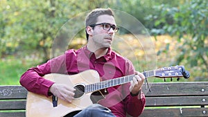 Man playing acoustic guitar and singing in park