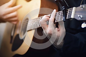 A man playing on an acoustic six-string guitar, holding his hand chords