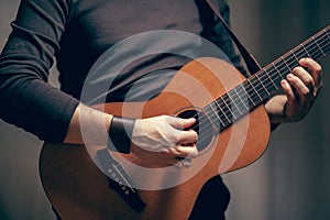 A man is playing on acoustic vintage guitar