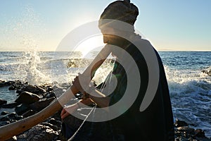Man playing on Austaralian didjireedoo insturment in sunshine at seashore photo