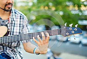Man playing bass acoustic guitar close-up