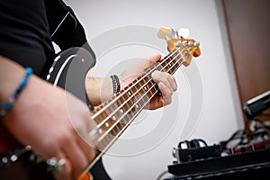 Man playing on a bass guitar, musical concert close up view.