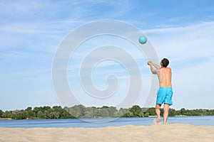 A man playing beach volleyball on hot sand on a sunny day.  Back view.  Sports  lifestyle