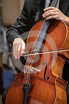 Man playing a cello using a bow in during a ceremony