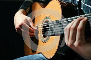 Man playing on classic guitar against dark background