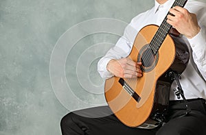 Man playing on classic guitar against light background