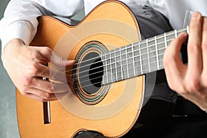 Man playing on classic guitar against light background