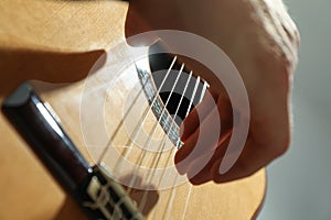 Man playing on classic guitar against light background