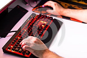 Man playing computer game on custom made desktop with joypad, keyboard, mouse.