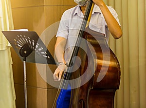 Man playing contra-bass with music notation. Double bass performer. Musician with string instrument on stage. Classic concert