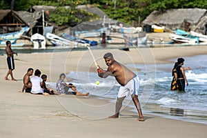 A man playing cricket on Arugam Bay beach in Sri Lanka.