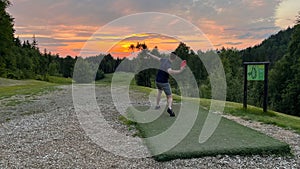 Man playing disc golf at the Krokhol Disc Golf Course in Norway against a golden sunset