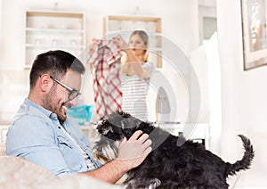 Man playing with dog and woman doing housework