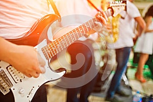 Man playing on electric guitar against band.