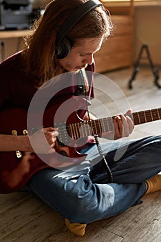 Man playing electric guitar on floor at sunny flat