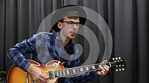 Man playing on electric guitar. Happy cute hippie male millennial performing lyric song on guitar and singing. Teenager in stylish