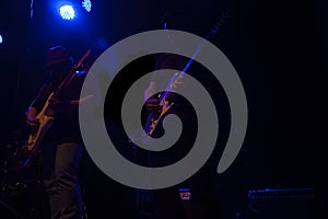 Man playing electric guitars in light against the backdrop of nightlife in Mexico City