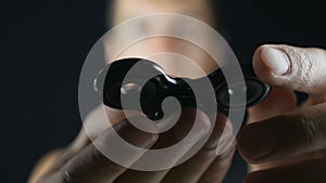 Man playing with fidget spinner. Close up spinner or fidgeting hand toy rotating on man`s hand at black background