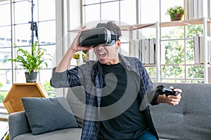 Man playing game using virtual reality headset and gamepads in the living room