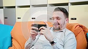 Man Playing Games on the Smartphone Indoors