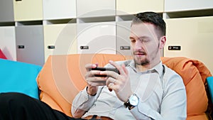 Man Playing Games on the Smartphone Indoors