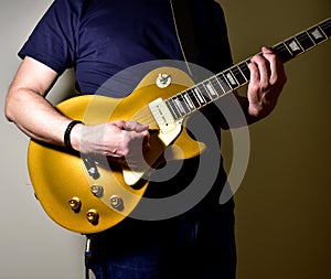 Man playing a gold top electric guitar with P90 pickups.