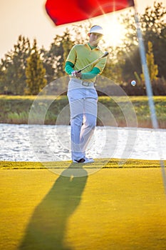 Man playing golf against sunset