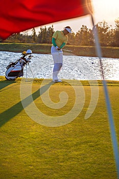 Man playing golf against sunset