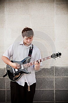 Man playing guitar against wall