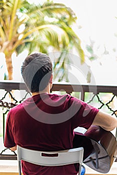 Man playing guitar on the balcony while spending time at home