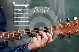 Man playing guitar chords displayed on a blackboard, Chord Am7