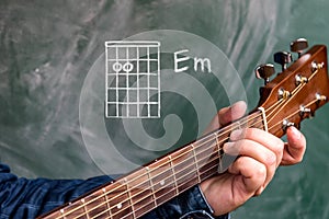 Man playing guitar chords displayed on a blackboard, Chord E minor